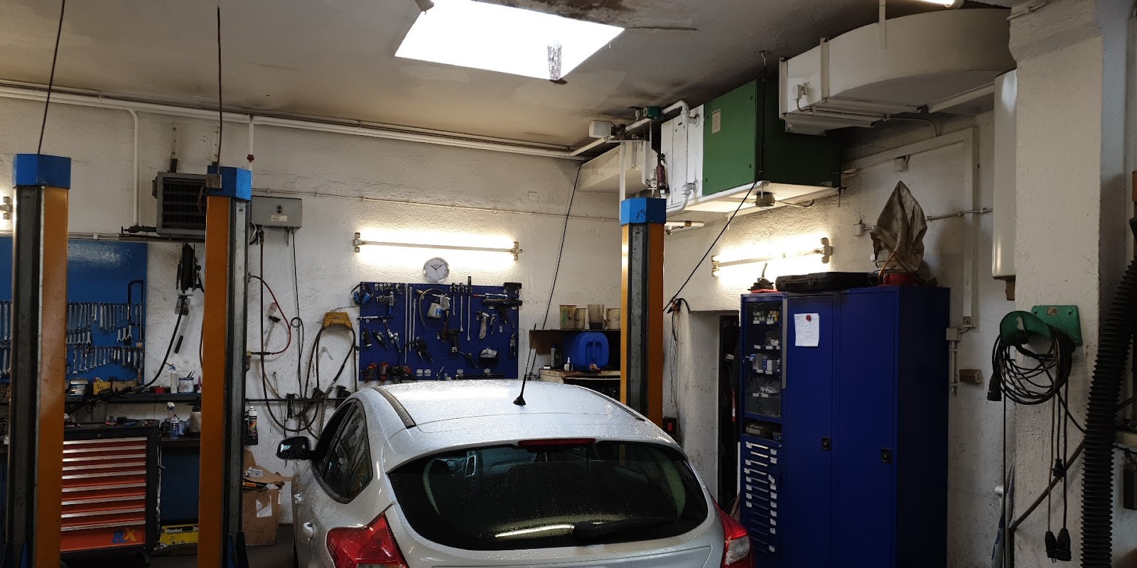 Werkstatthalle mit zwei Hebebühnen, Werkzeugwand und einem Ford auf dem Stellplatz